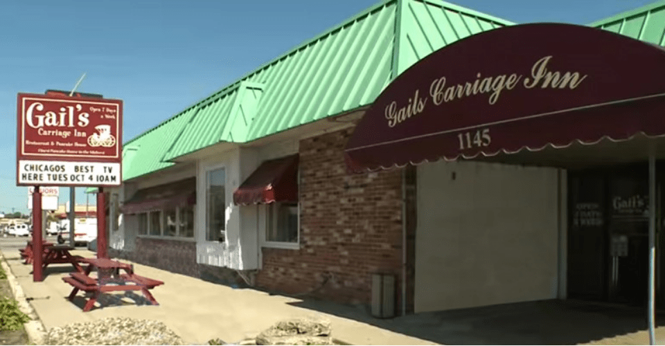 Exterior view of Gail's Carriage Inn, featuring a green roof, brick facade, and a sign displaying the restaurant's name.