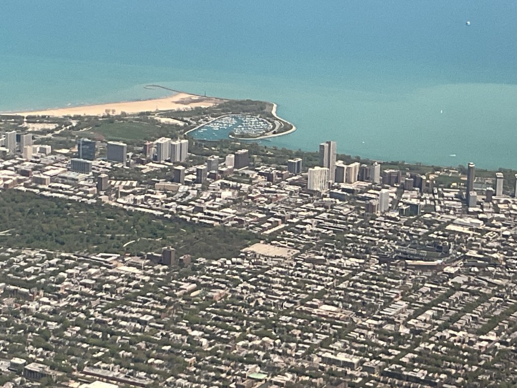 Aerial view of Chicago featuring a mix of buildings, green spaces, and Lake Michigan in the background.