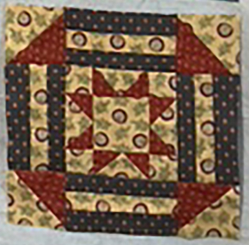 A colorful patchwork quilt block featuring star and striped patterns in red, yellow, and blue fabrics.
