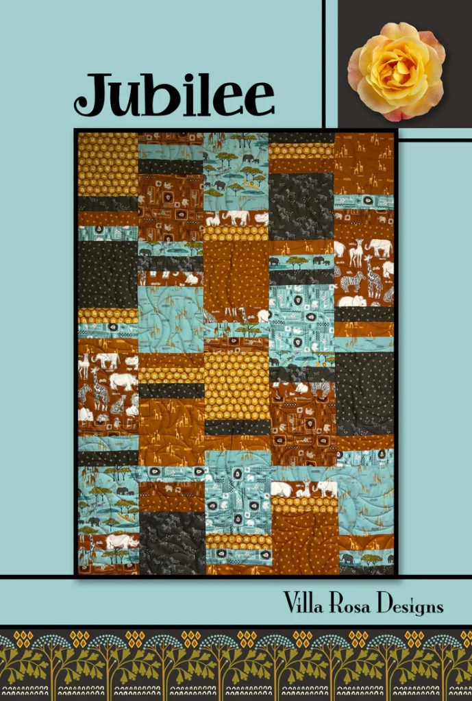 A vibrant quilt titled 'Jubilee' featuring an assortment of patterned batik fabrics in earthy tones of brown, turquoise, and black, designed by Villa Rosa Designs.