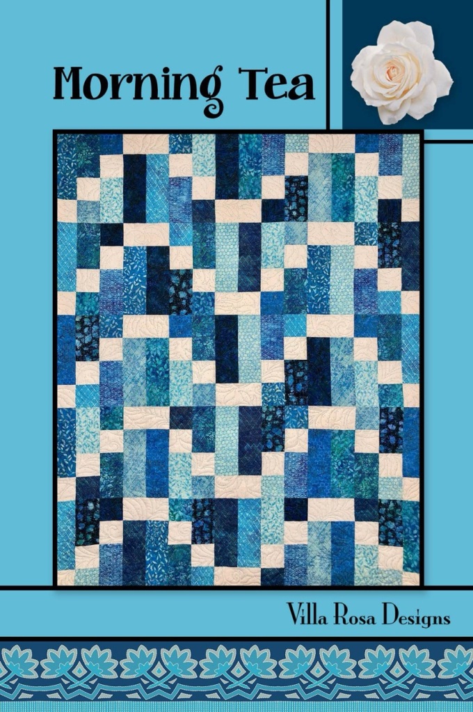 A quilt design titled 'Morning Tea' featuring various shades of blue fabrics arranged in a patchwork pattern, with a light background and floral design at the top corner.