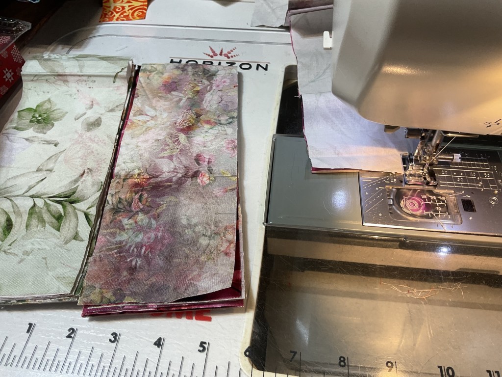 Fabric strips arranged on a sewing machine ready for quilting.