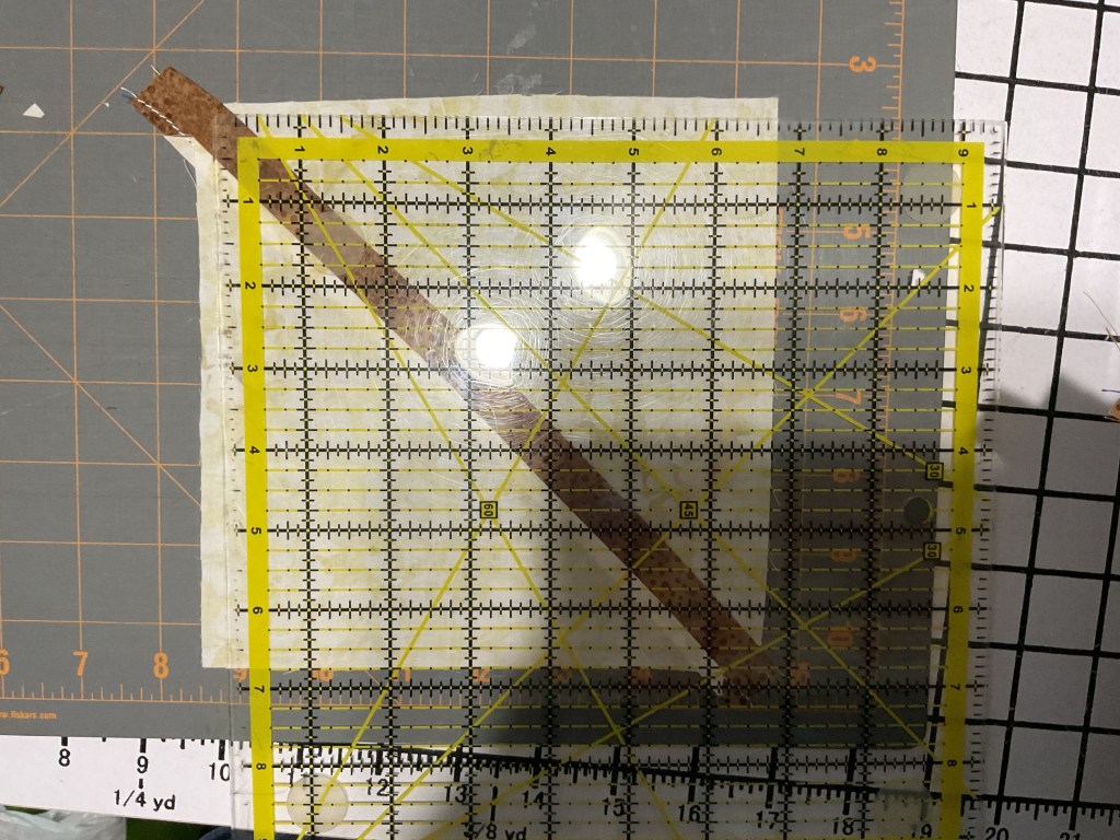 A quilting ruler placed over fabric on a cutting mat, showcasing measurement lines and a partially cut fabric strip.