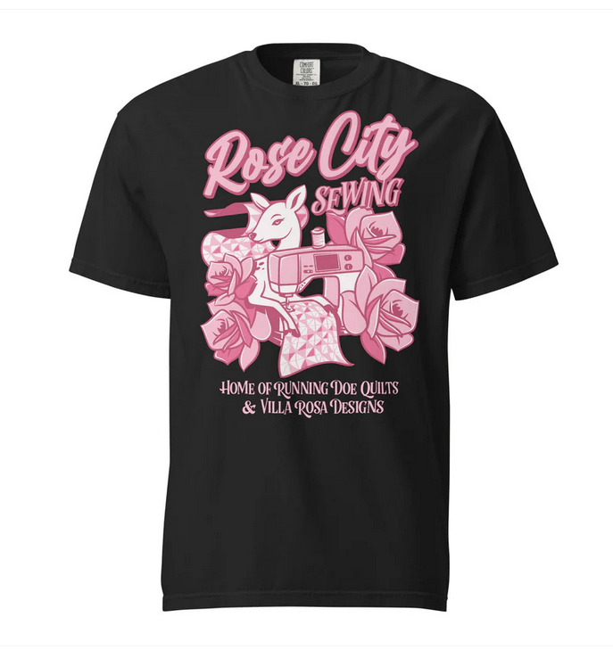 Black t-shirt featuring a pink graphic design with a deer, sewing machine, and roses, labeled 'Rose City Sewing - Home of Running Doe Quilts & Villa Rosa Designs'.