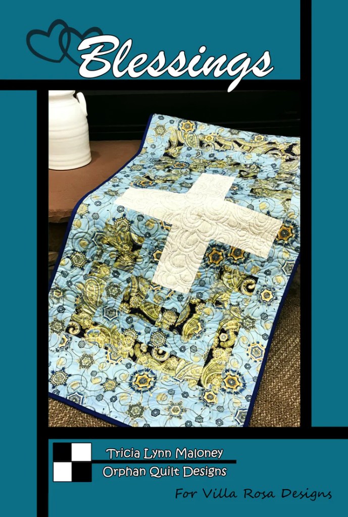 Quilt pattern titled 'Blessings' featuring a blue and gold design with a white cross, designed by Tricia Lynn Maloney for Villa Rosa Designs.