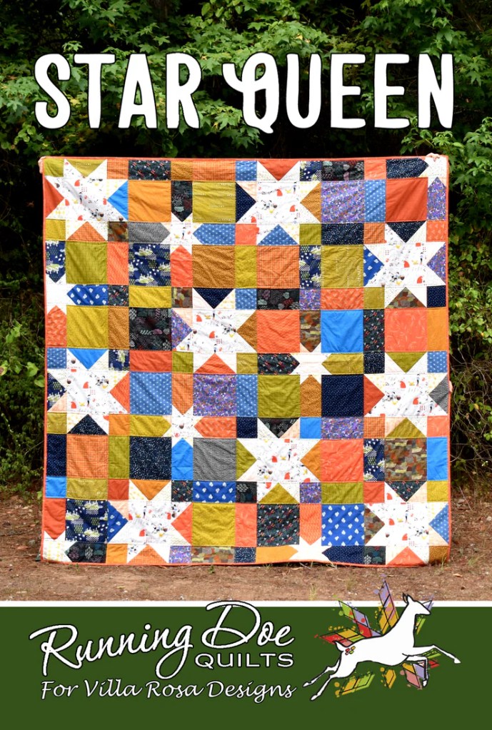A colorful quilt titled 'Star Queen' displayed outdoors, featuring a patchwork design with star motifs in various colors.