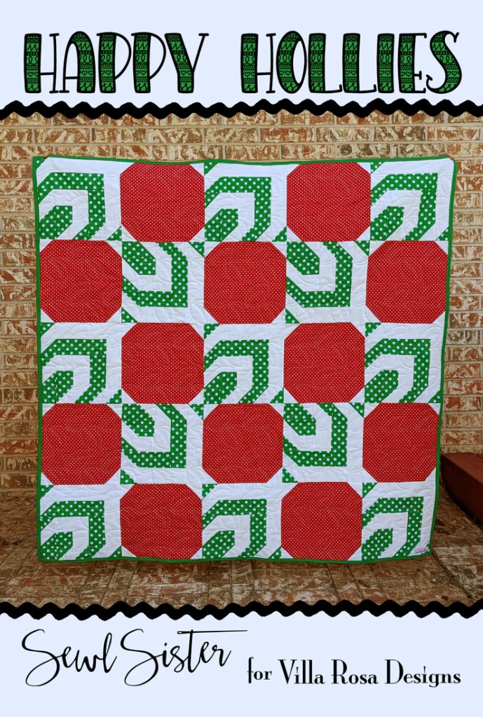 A vibrant holiday-themed quilt titled 'Happy Hollies' featuring bold red and green fabrics with polka dot patterns, displayed against a brick background.