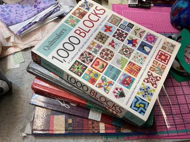 A stack of quilting books with the top book titled 'Quiltmaker's 1000 Blocks', showcasing various quilt block designs on its cover.