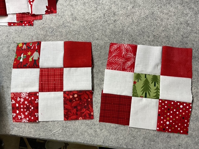 Two completed Nine Patch quilt blocks featuring a mix of red and white fabrics, with one block incorporating a green Christmas tree print.