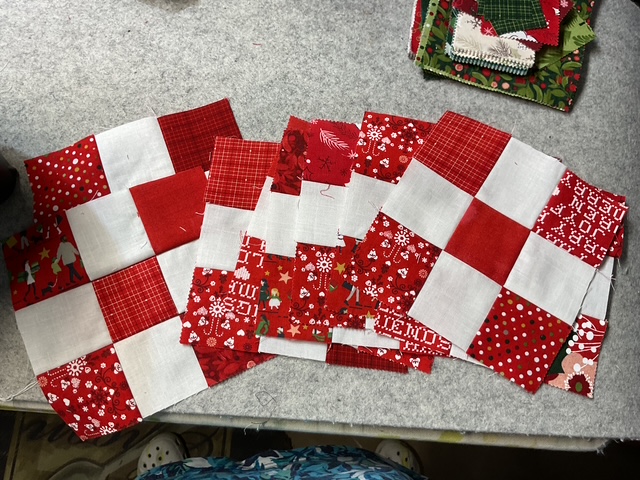 A collection of red and white quilt blocks arranged on a crafting surface, showcasing various patterns and textures.