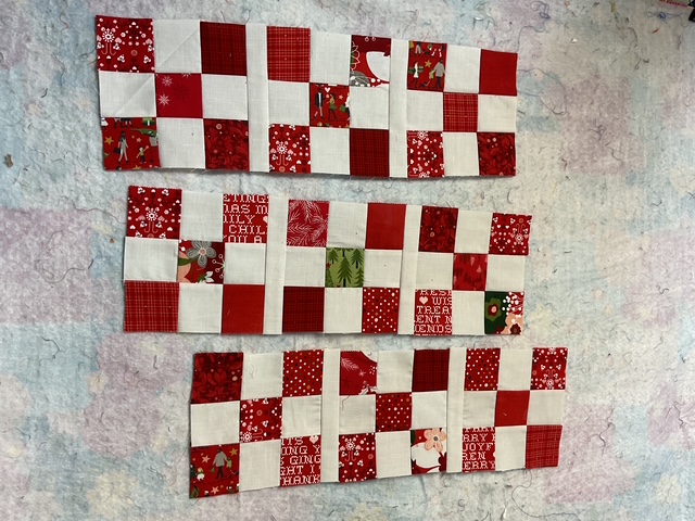Three rows of Nine Patch quilt blocks in red and white fabrics, featuring holiday patterns.