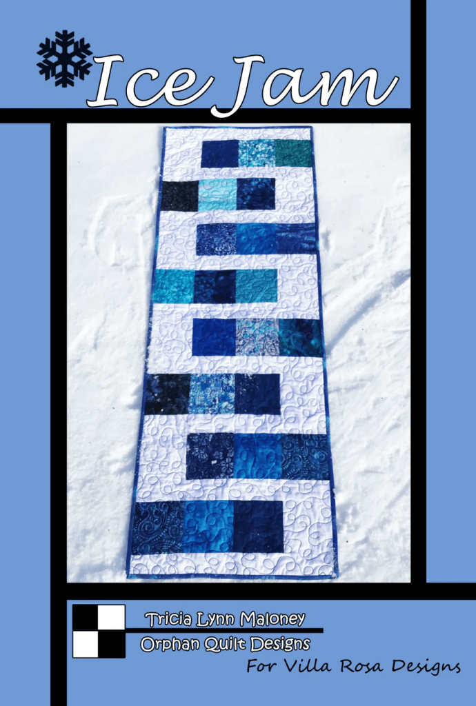 Cover of the pattern titled 'Ice Jam' featuring a quilt with varying shades of blue squares on a light blue background, set against a snowy surface.