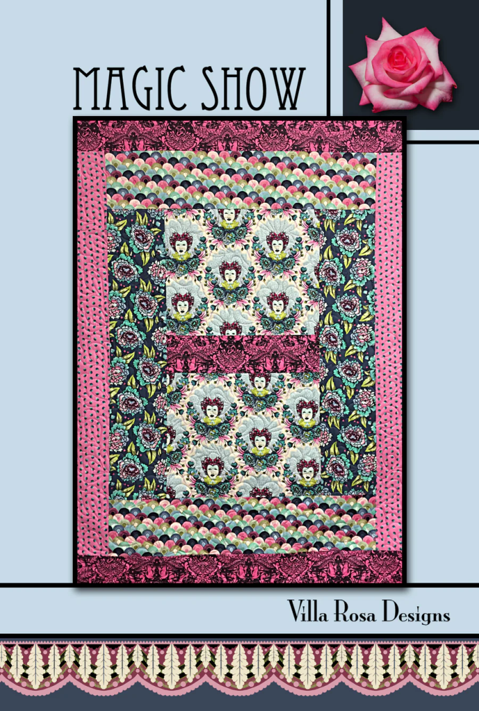 A colorful quilt design titled 'Magic Show' by Villa Rosa Designs, featuring floral patterns and whimsical motifs, bordered with pink and patterned fabrics.