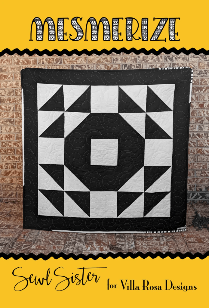 A black and white quilt featuring geometric patterns displayed against a brick wall with a yellow background and decorative text that says 'Mesmerize' and 'Sewl Sister for Villa Rosa Designs'.