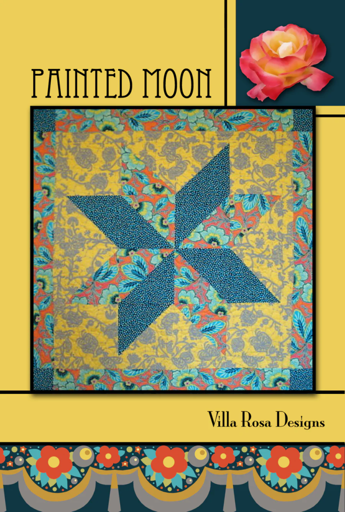 A colorful quilt design featuring a geometric pattern titled 'Painted Moon' by Villa Rosa Designs, with a blue and yellow color scheme and floral accents.