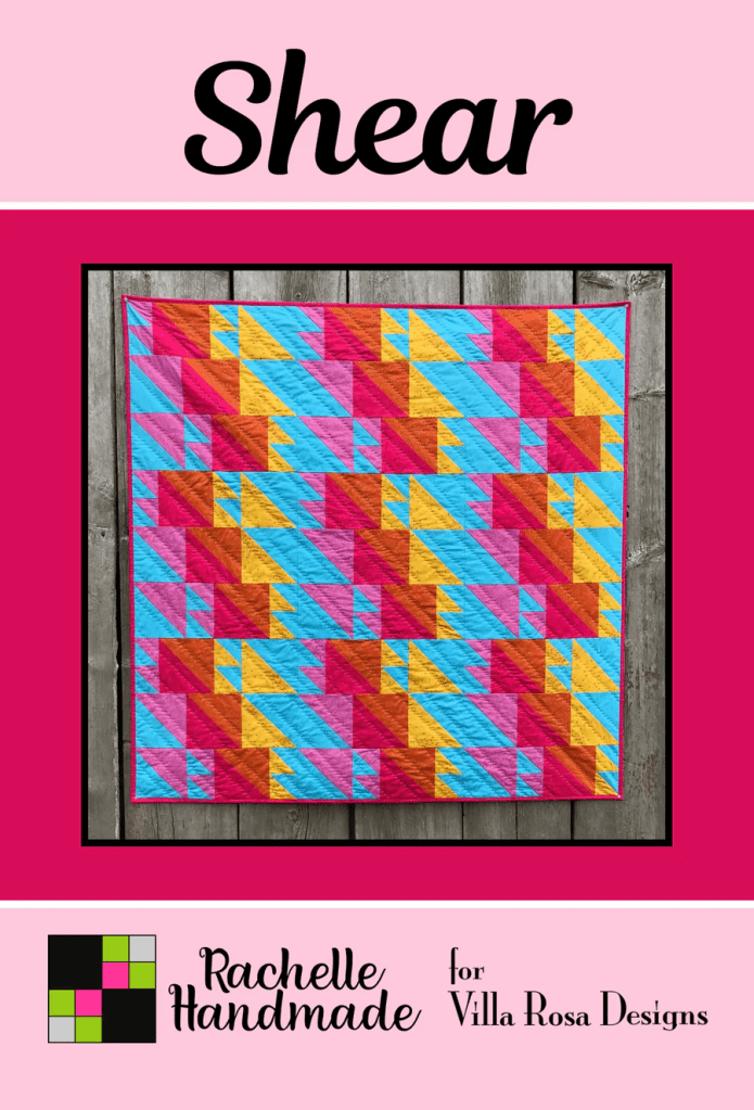 A colorful quilt design featuring geometric patterns in vibrant shades of pink, blue, yellow, and orange, titled 'Shear' by Rachelle Handmade for Villa Rosa Designs.