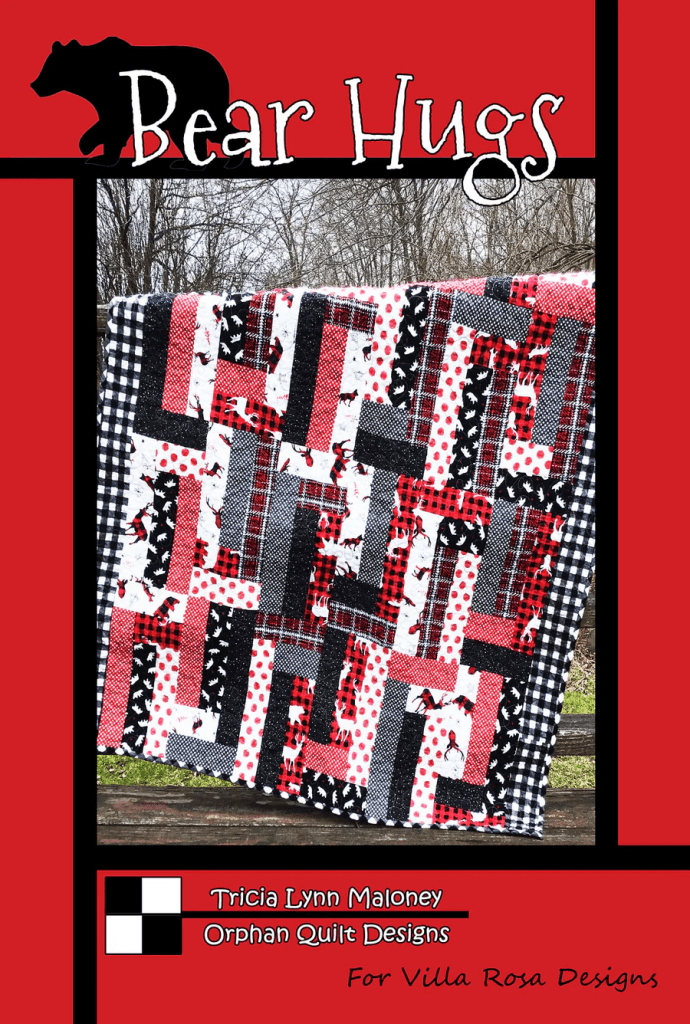 A quilt titled 'Bear Hugs' featuring a patchwork design with red, black, and white fabrics, displayed outdoors against a natural backdrop, with a bear silhouette above the title.