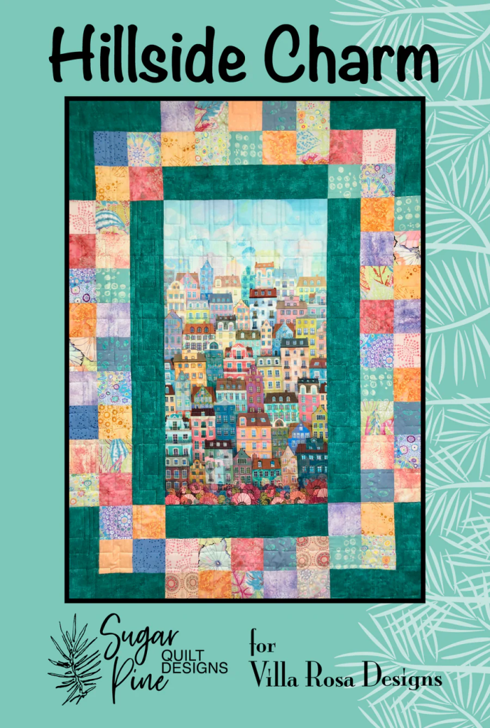 Quilt pattern titled 'Hillside Charm' featuring a colorful patchwork design with a central illustration of houses on a hillside, framed by a variety of vibrant borders.