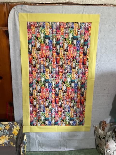 A colorful fabric panel featuring a repeated pattern of cartoon animals, framed with a yellow border.