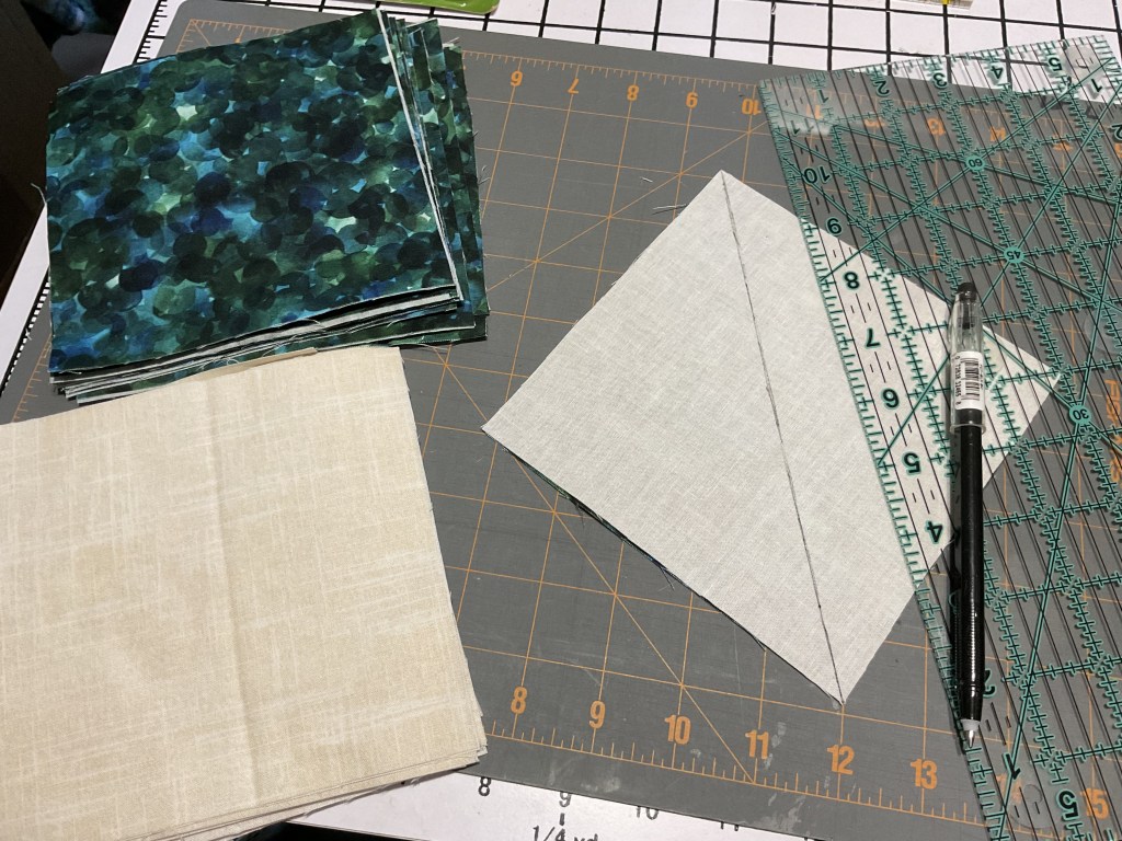 A workspace showing various fabric squares, including printed and solid colors, with a ruler and a pen for cutting and measuring fabric.