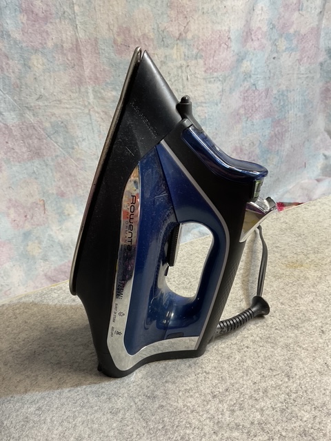 A blue and black Rowenta steam iron positioned on a gray surface.