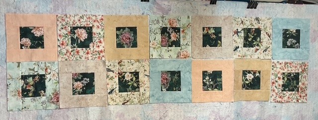 A patchwork layout featuring a series of floral squares surrounded by solid-colored borders in a variety of pastel shades.
