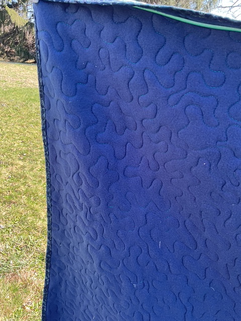 Close-up of a dark blue fabric with a quilted texture featuring a pattern of wavy lines.