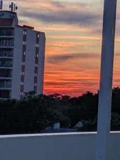 A colorful sunset view with shades of orange and pink in the sky, partially obscured by a building.