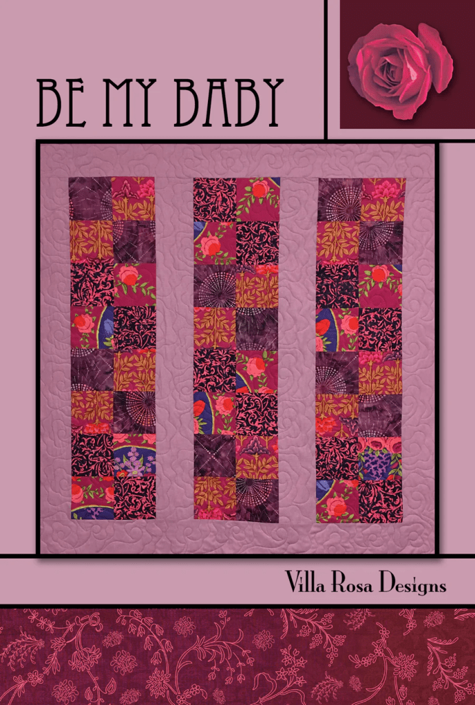 A quilt design featuring three vertical panels of colorful patchwork patterns in vibrant reds, purples, and floral prints, with the title 'BE MY BABY' and 'Villa Rosa Designs' branding.