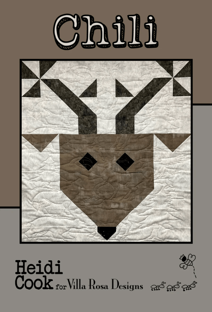 A quilt with a deer head design in shades of brown, featuring geometric patterns. The title 'Chili' is at the top, with the name 'Heidi Cook for Villa Rosa Designs' displayed below.
