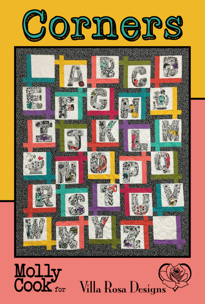 A colorful quilt featuring letters A to Z, each surrounded by patterned fabric squares and decorative motifs, designed by Molly Cook for Villa Rosa Designs.