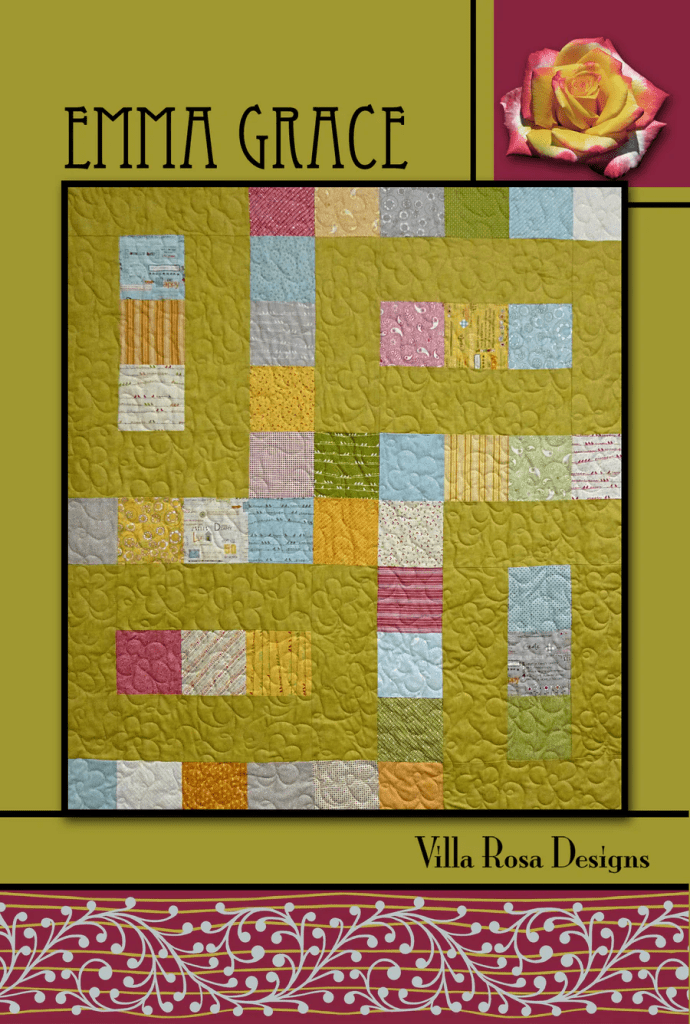 A colorful quilt design featuring various patterned squares on a green background, with the title 'Emma Grace' and a rose graphic in the upper right corner. The design is framed with a decorative border at the bottom.