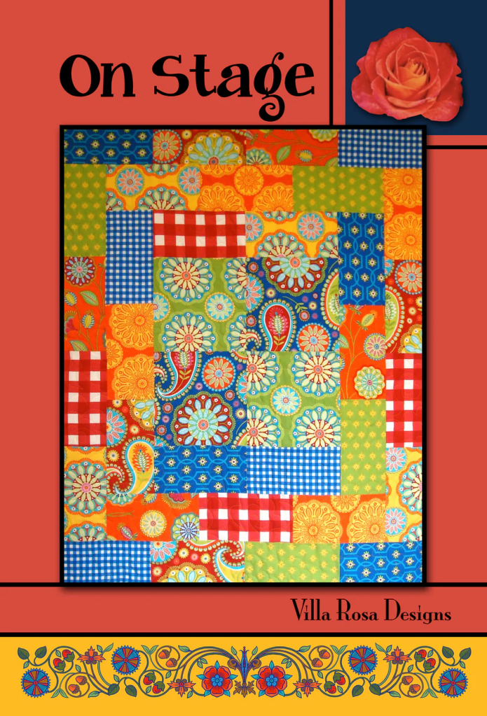 Colorful quilt design titled 'On Stage' by Villa Rosa Designs, featuring a patchwork of vibrant patterns, including florals, paisleys, and checkered designs, set against a red background with a rose graphic.