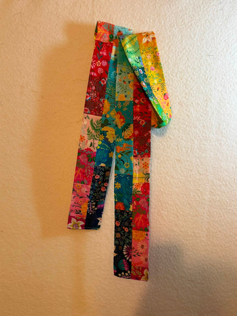 A collection of brightly colored fabric strips with floral patterns hanging on a wall.