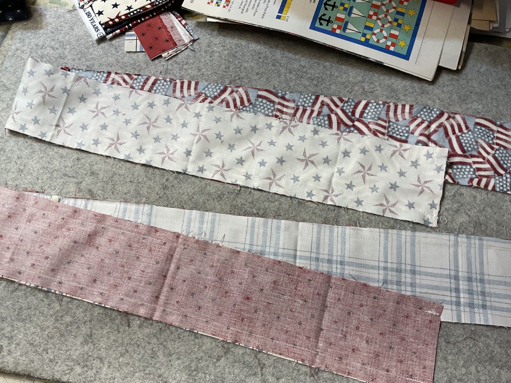 Three strips of fabric laid out on a gray felt surface, featuring patriotic designs in red, white, and blue, including stars and stripes.