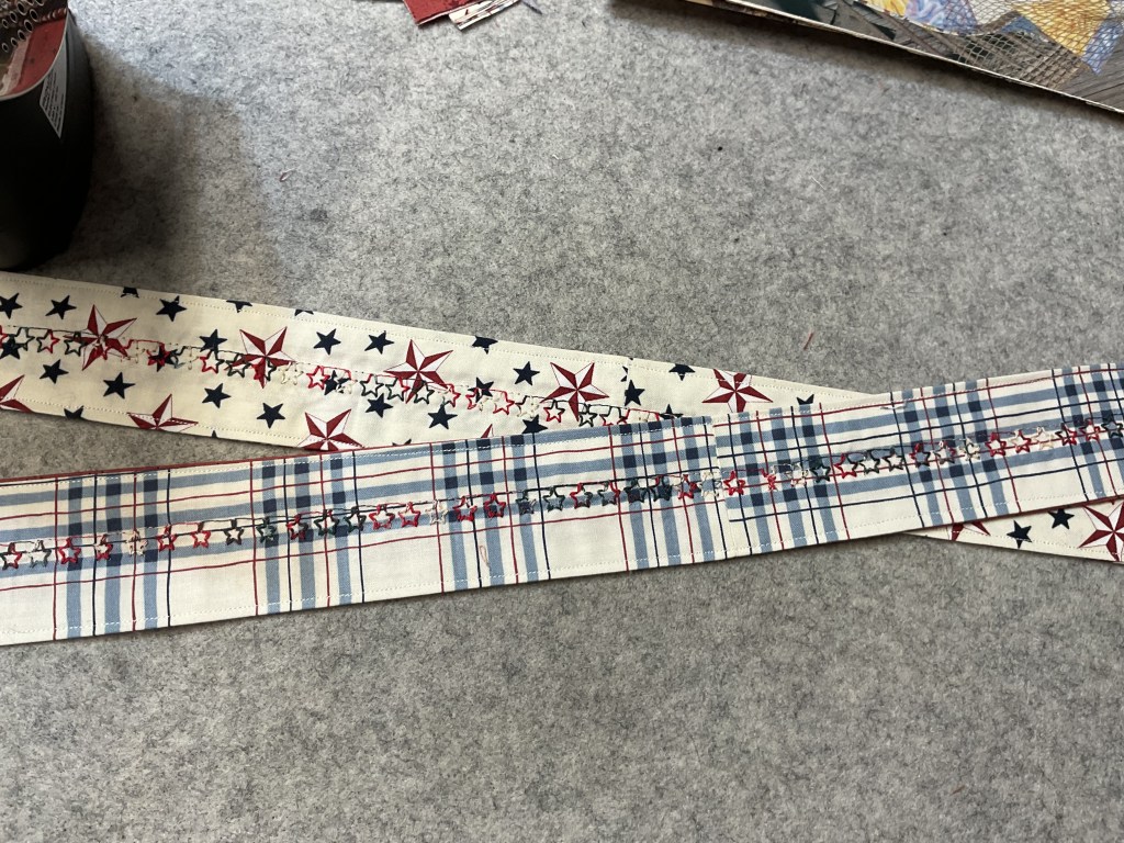 Two strips of decorative fabric with red, white, and blue patterns, one featuring stars and the other with plaid and stars, laid on a gray surface.