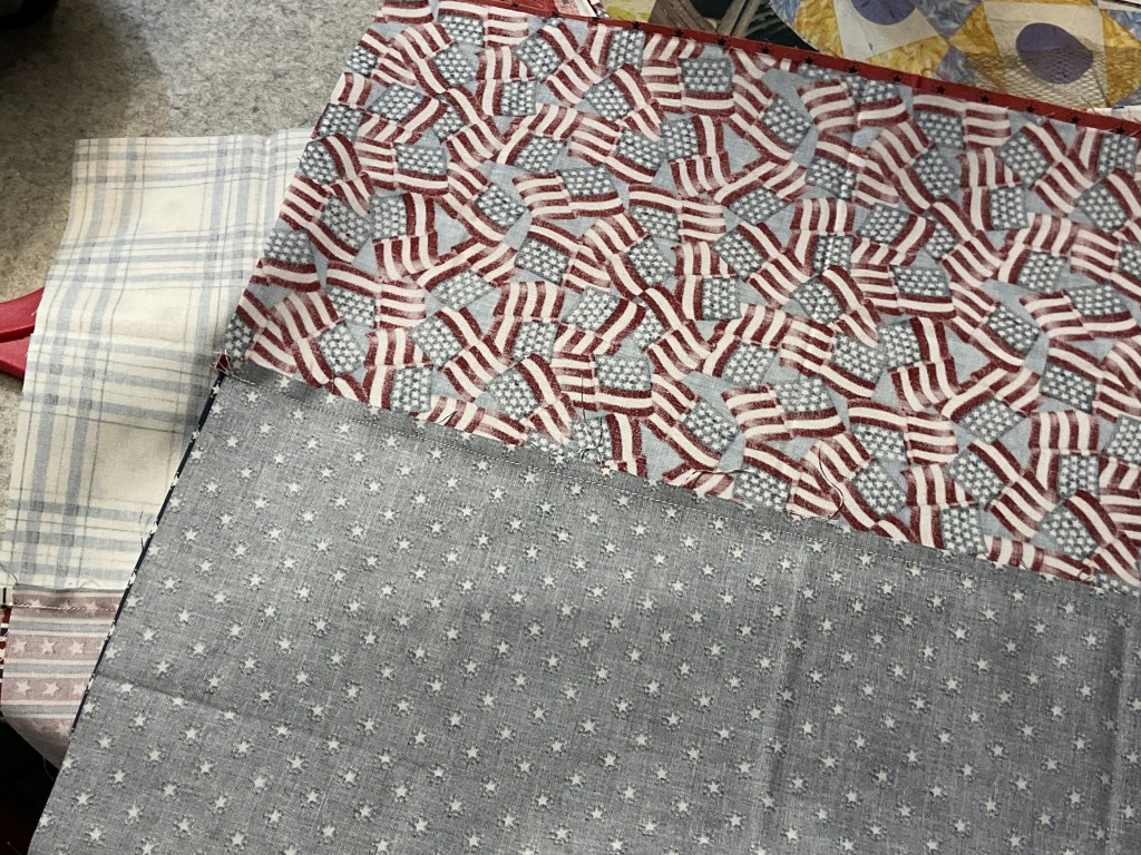 Assorted pieces of fabric featuring patriotic patterns, including American flags, a checkered design, and a star print.