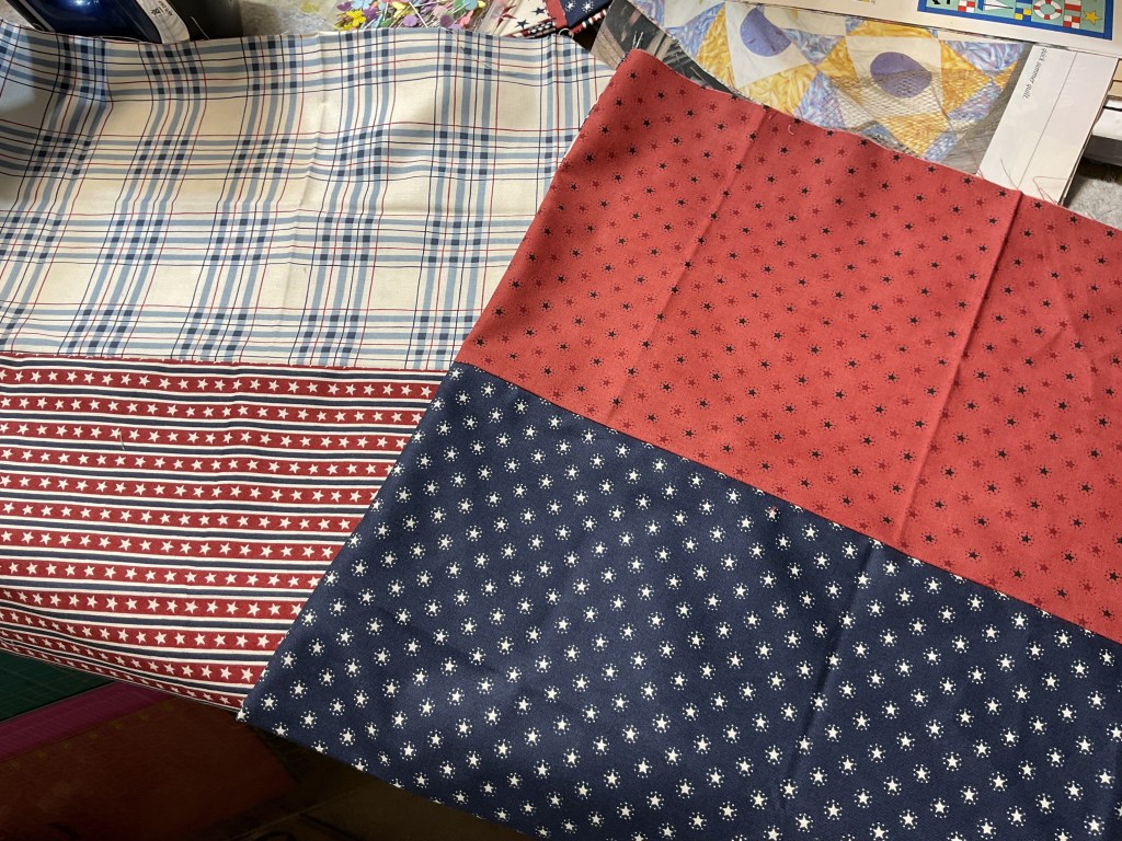 A selection of four fabric swatches featuring various patterns: a light blue plaid, a red and white striped fabric with stars, a solid red fabric, and a navy blue fabric with white floral designs.