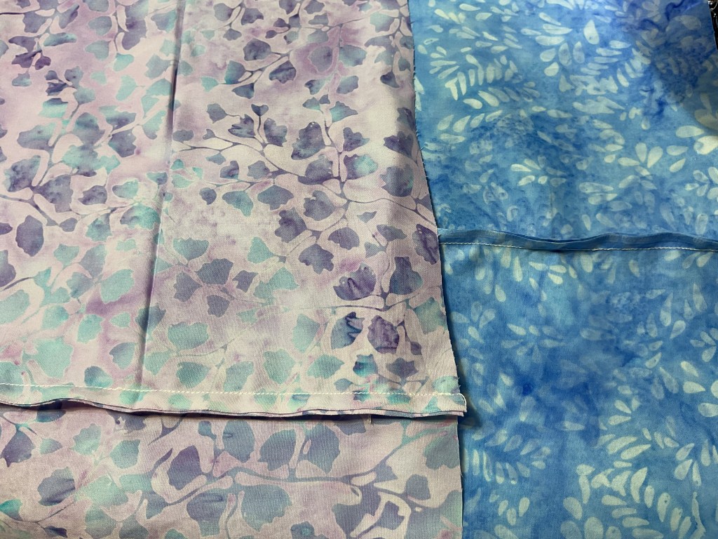 Two fabric pieces showcasing floral and leaf patterns, one in pastel colors with purple and teal hues and the other in various shades of blue.