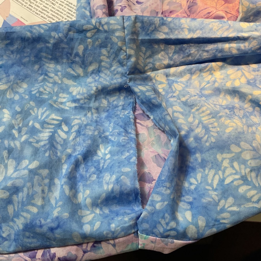 Close-up of fabric with a blue and white leaf pattern, with a pink floral print visible underneath.