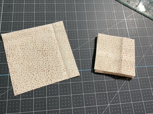 Two pieces of patterned paper on a crafting mat, one larger and one smaller, both with a speckled design.