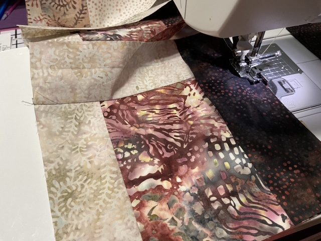 A close-up view of a sewing machine stitching together colorful fabric pieces, showcasing various patterns and textures.