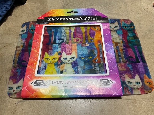 Silicone pressing mat with a colorful cat design, featuring various stylized cats in vibrant colors, packaged with a hanging tab.